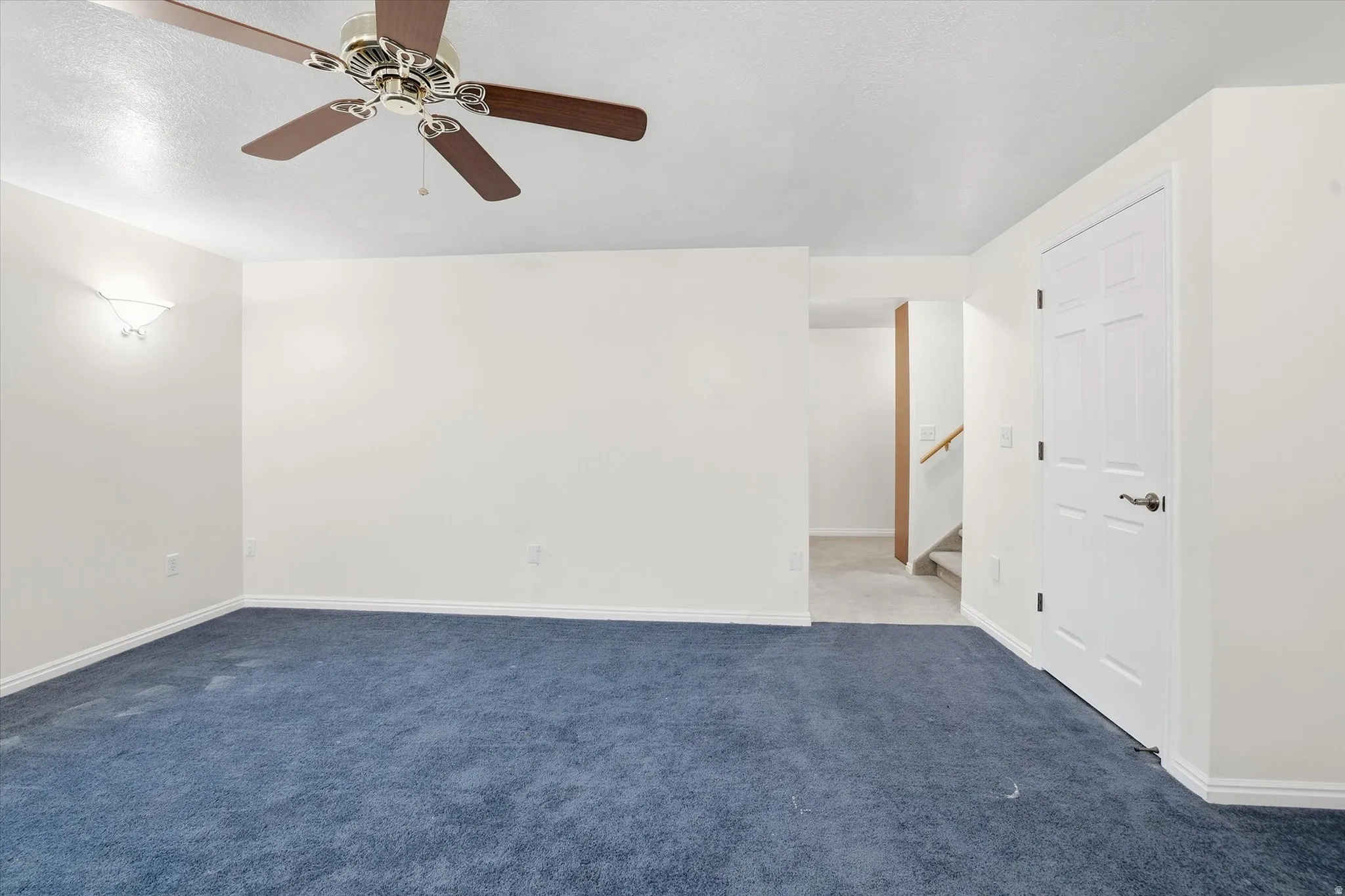 Carpeted spare room with baseboards and a ceiling fan
