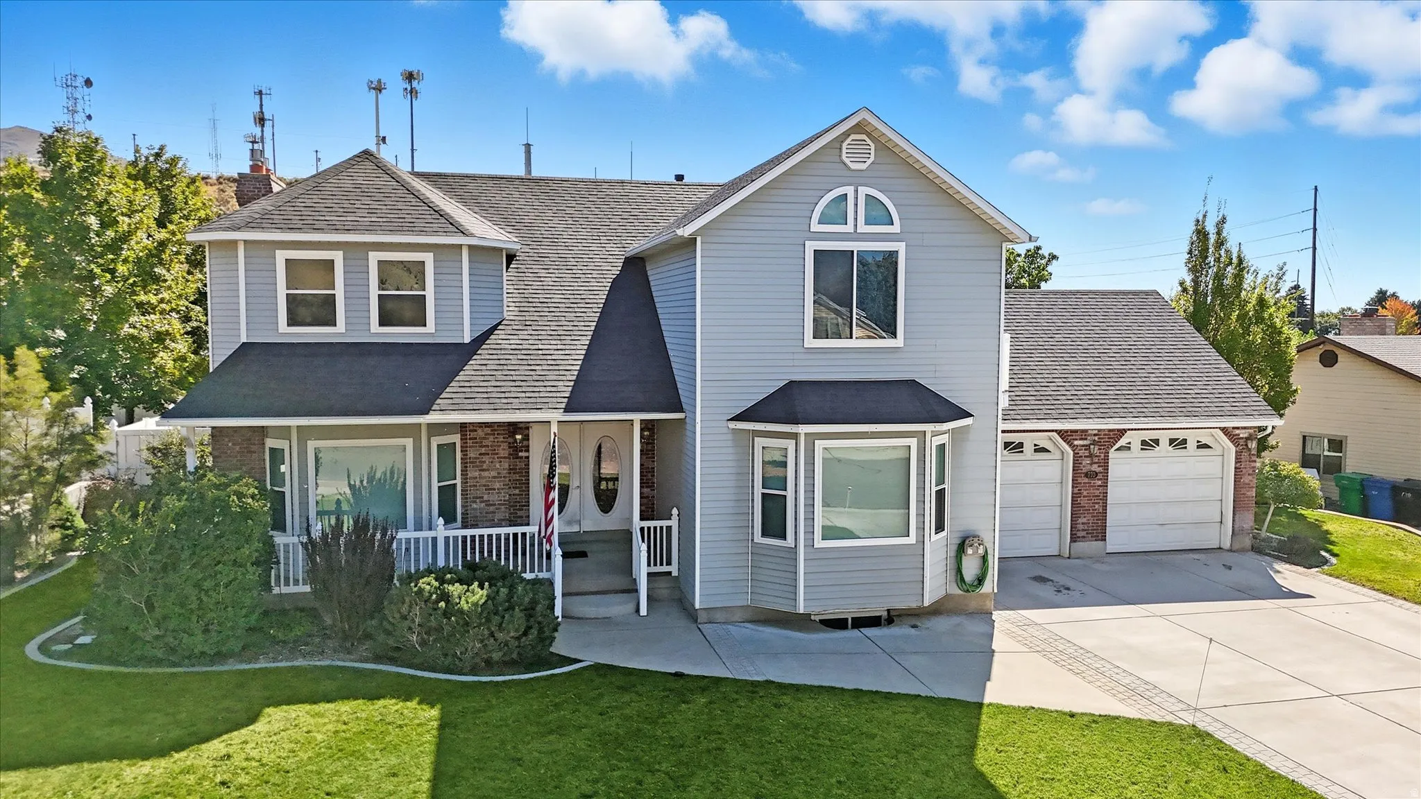 Traditional-style home featuring brick siding, a porch, a garage, and roof with shingles