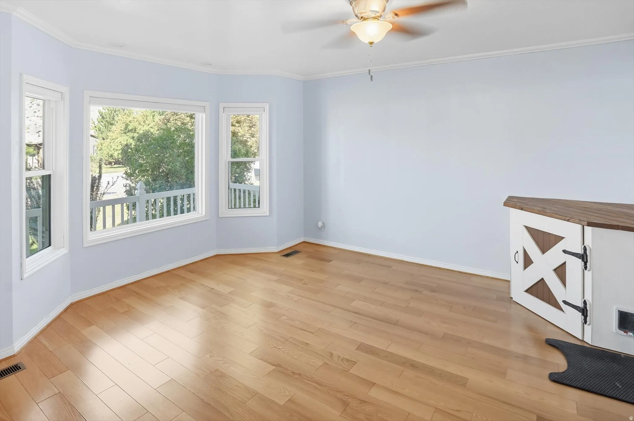 Unfurnished room with light wood finished floors, a ceiling fan, and crown molding