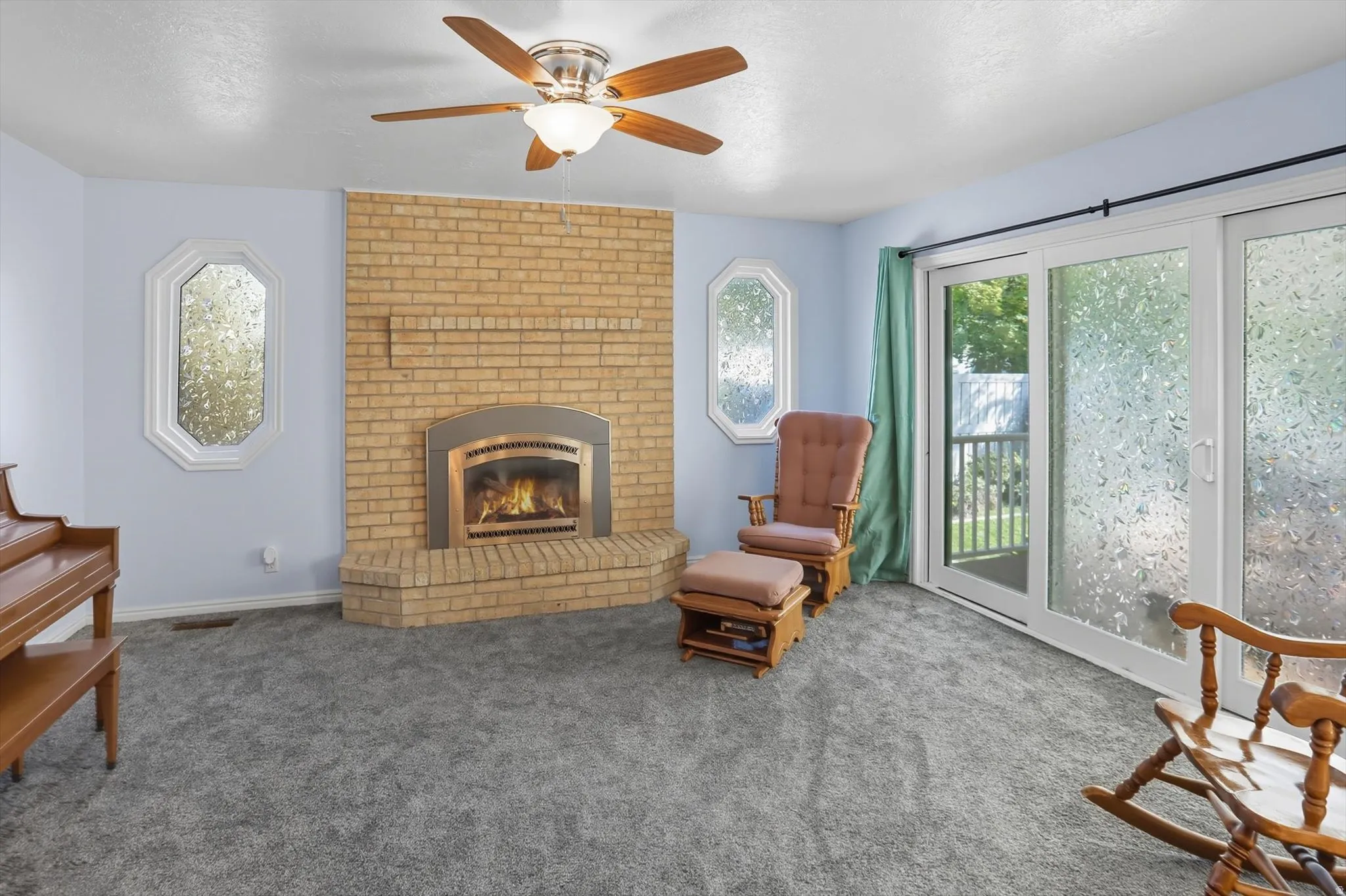Sitting room with carpet flooring, a fireplace, a ceiling fan, and a textured ceiling