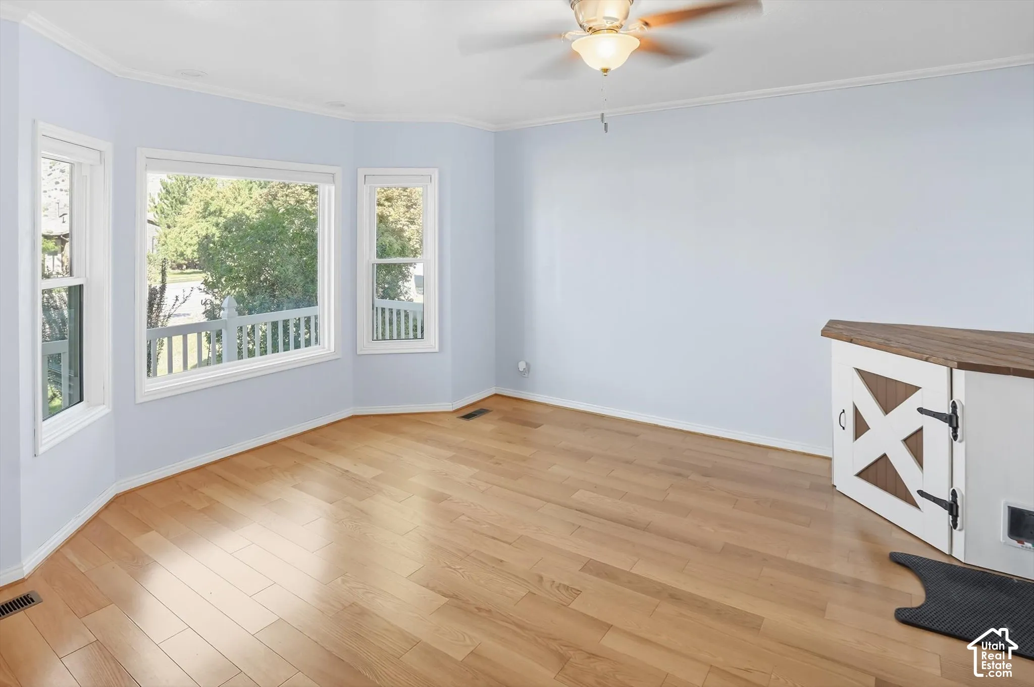 Unfurnished room with light wood finished floors, a ceiling fan, and crown molding