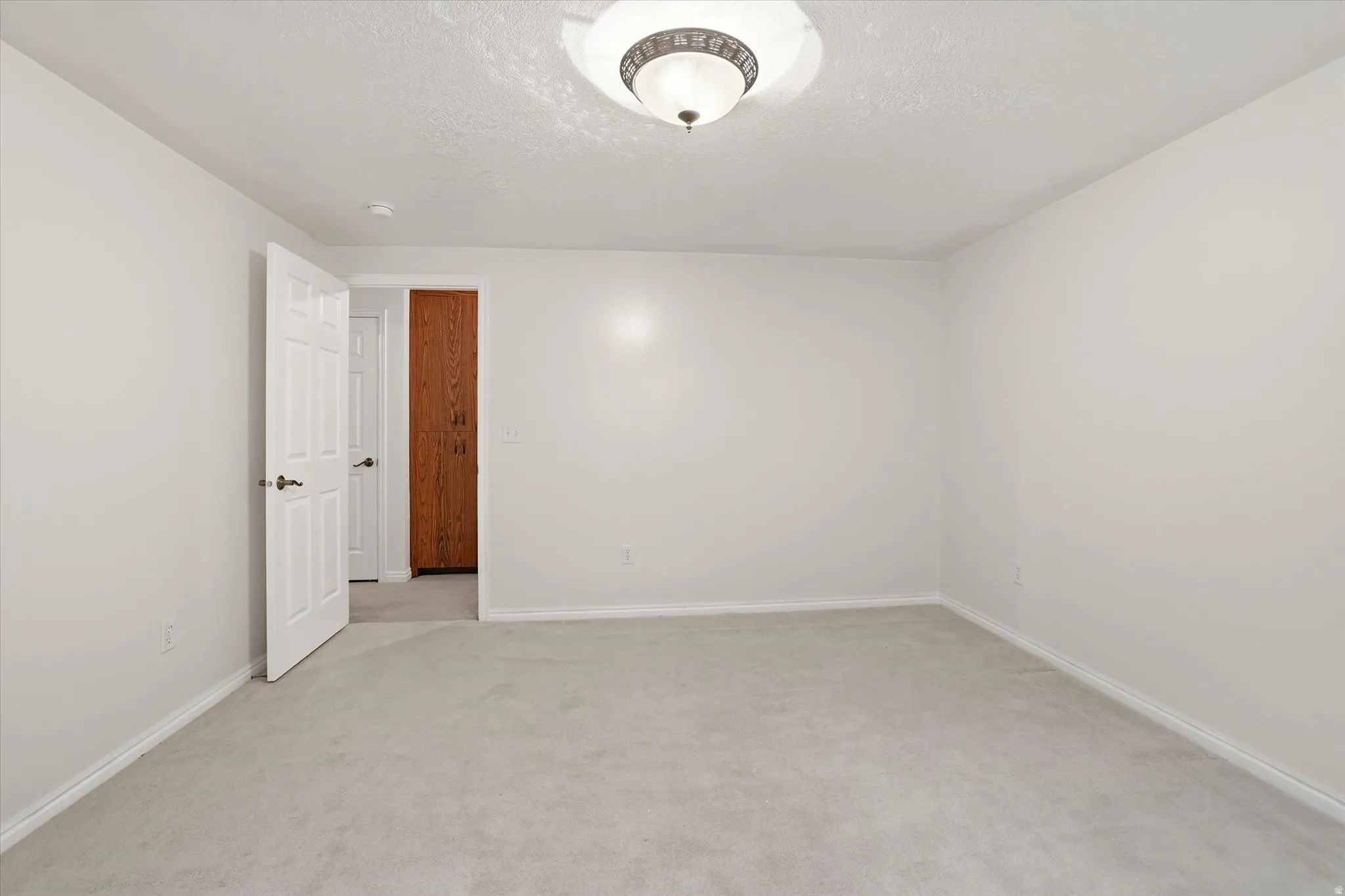 Empty room featuring light carpet and a textured ceiling