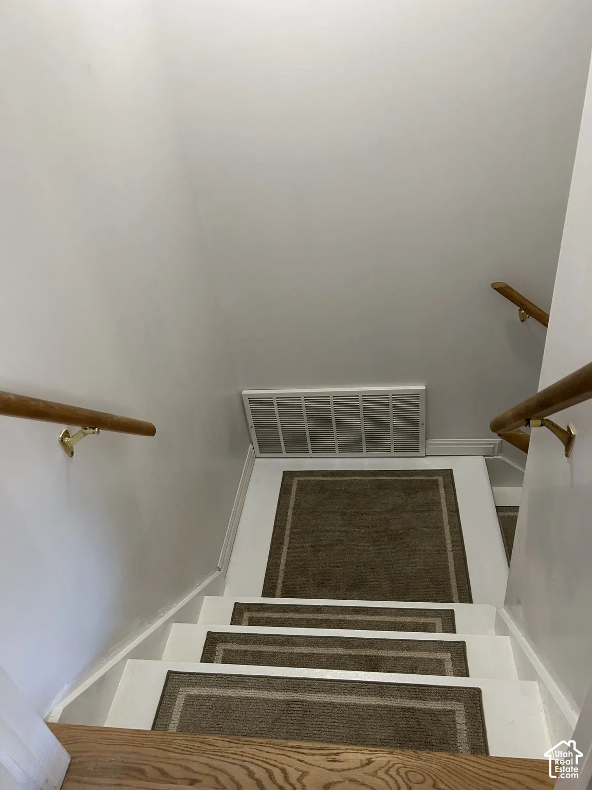 Staircase with white-painted treads and brass-toned handrails mounted on brackets