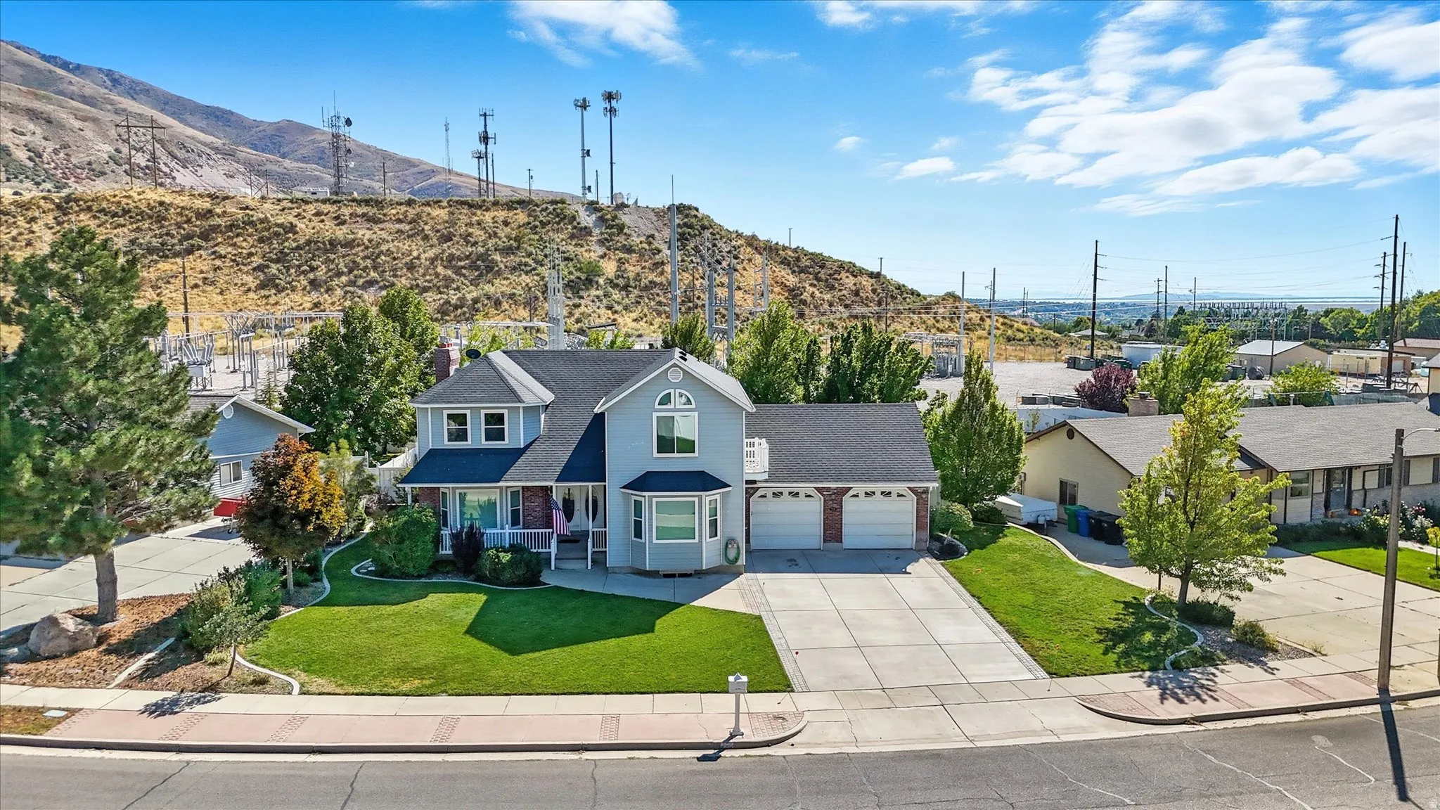 Traditional home with a front lawn, driveway, a residential view, an attached garage, and a mountain view