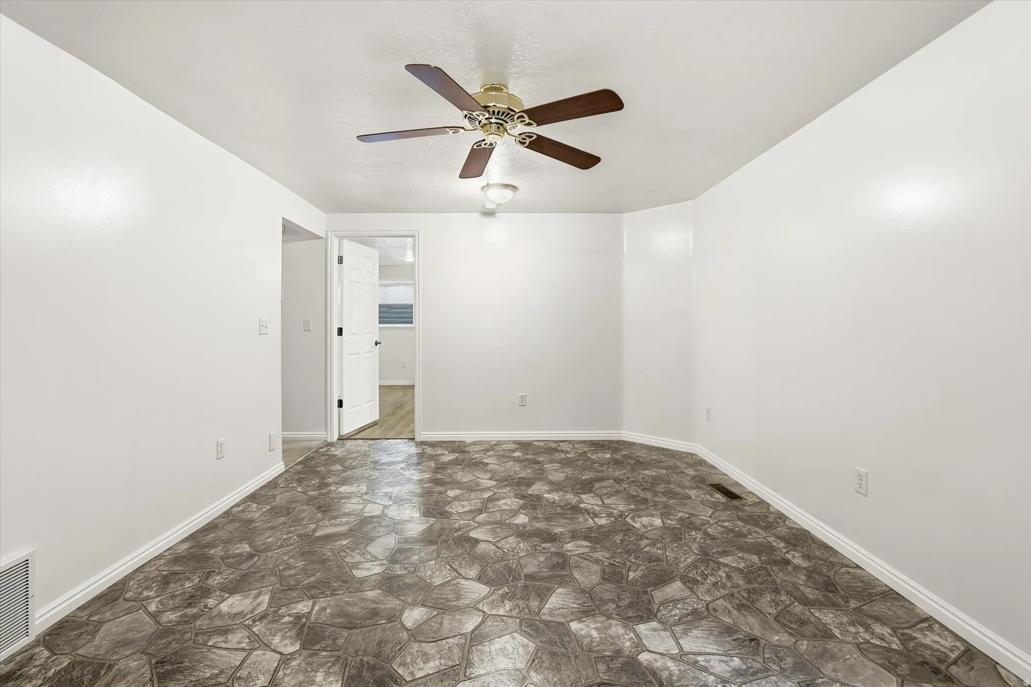 Unfurnished room with stone floors and ceiling fan