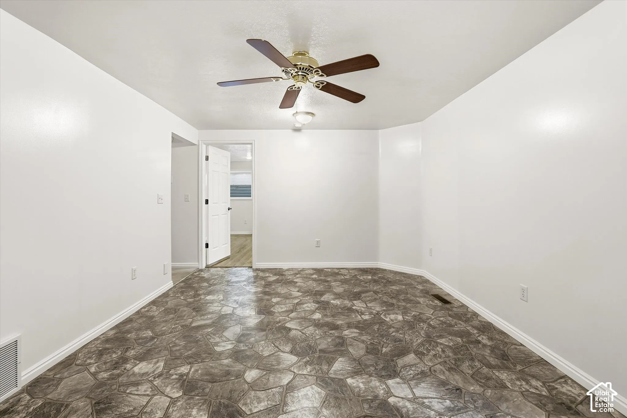 Unfurnished room with stone floors and ceiling fan