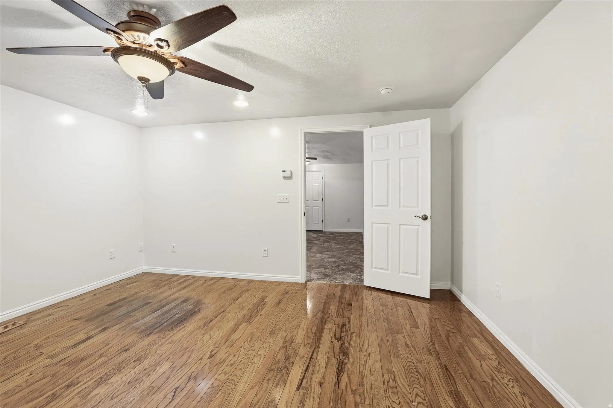 Unfurnished room with dark wood-type flooring and ceiling fan