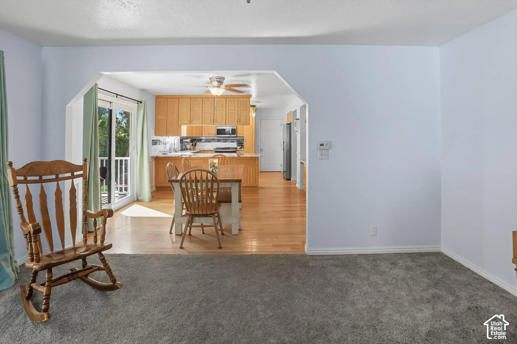 Kitchen with arched walkways, light carpet, a peninsula, stainless steel appliances, and a breakfast bar area