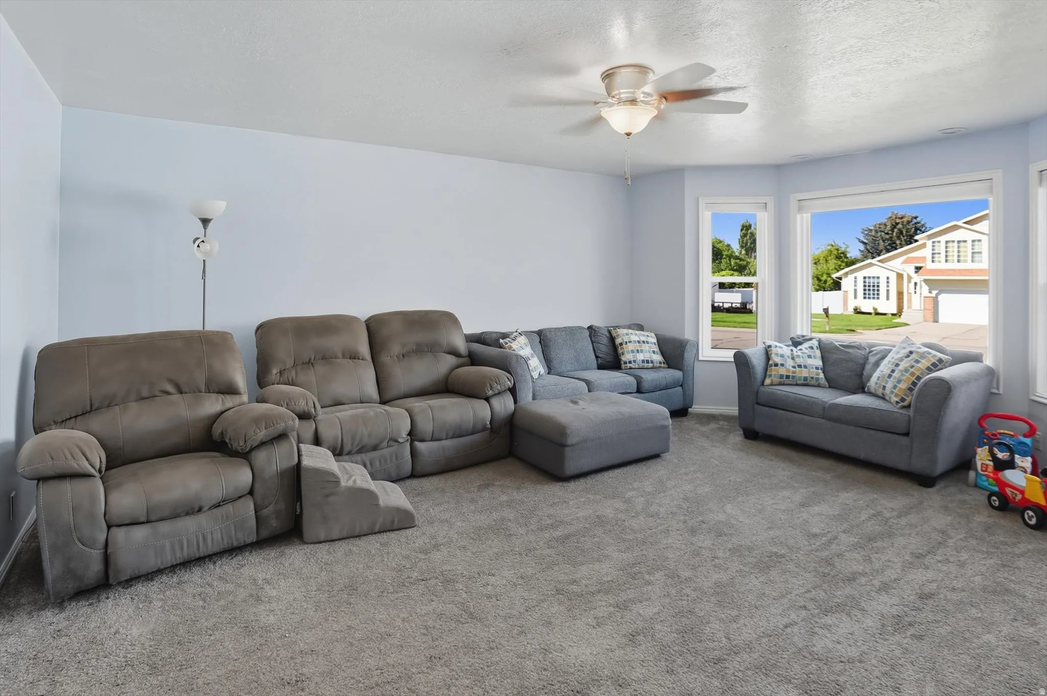 Carpeted living room featuring a ceiling fan and a textured ceiling