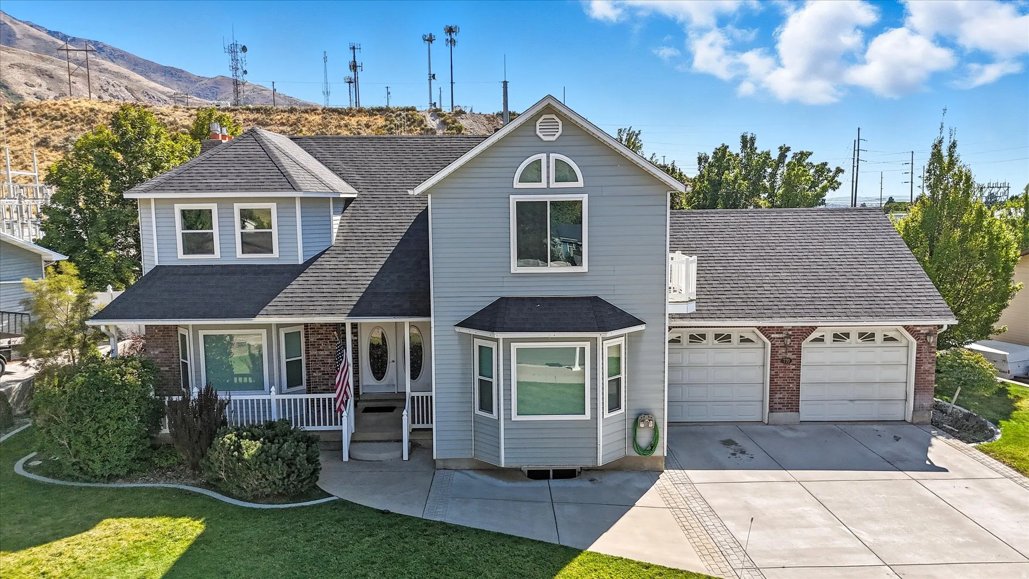 Traditional-style house with roof with shingles, a porch, concrete driveway, and brick siding