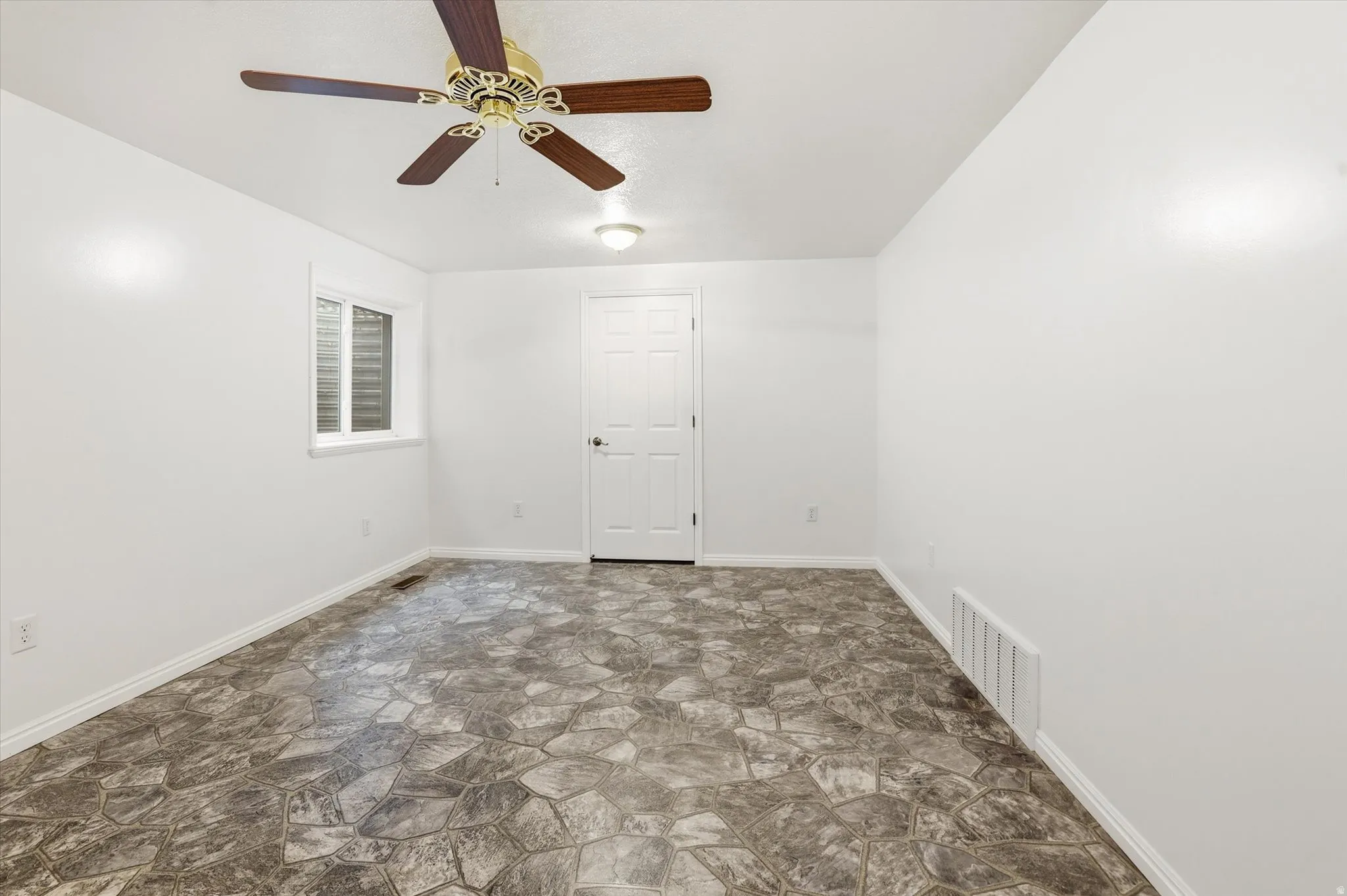 Spare room featuring stone floors and ceiling fan
