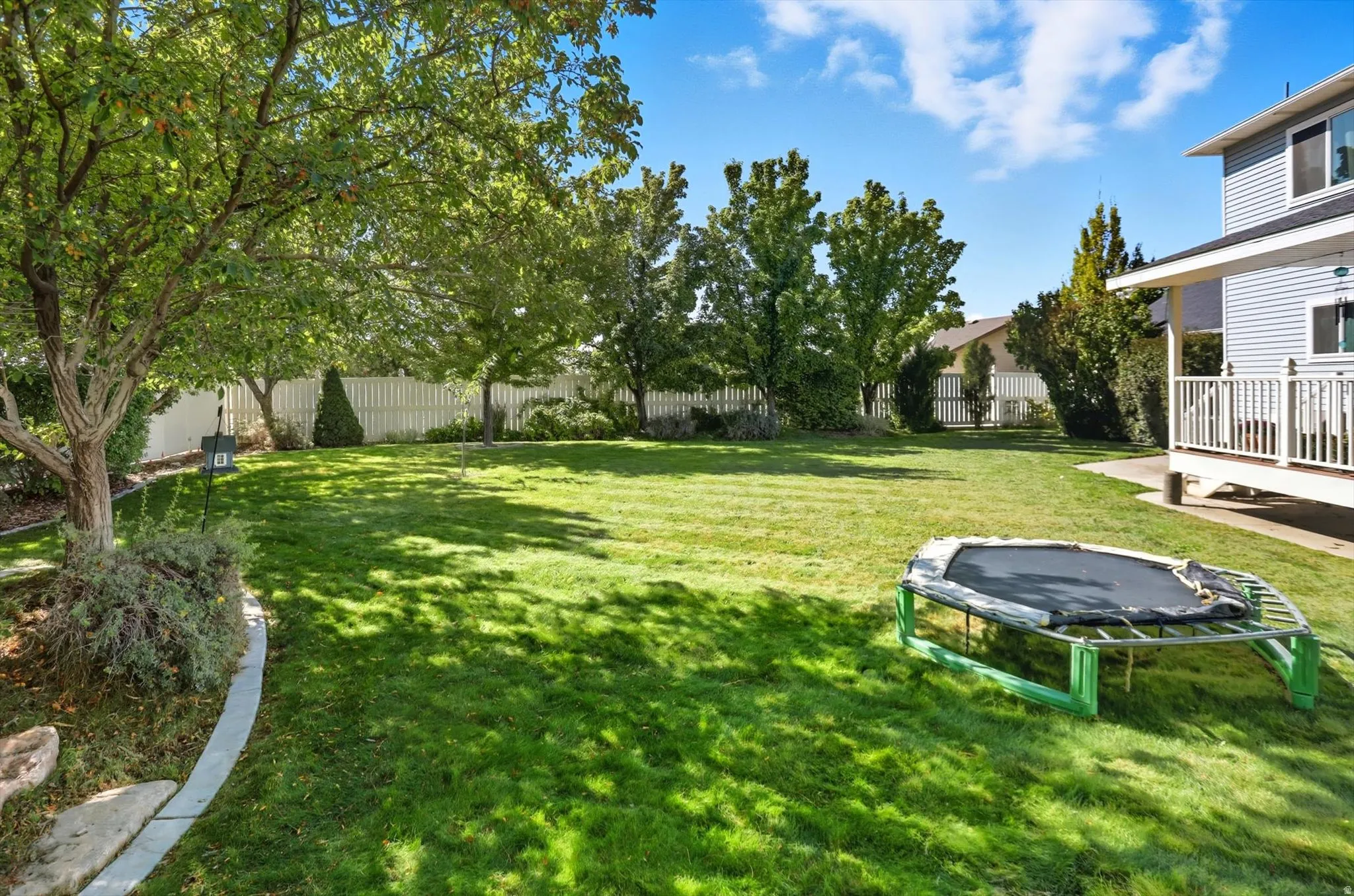 Fenced backyard featuring a trampoline