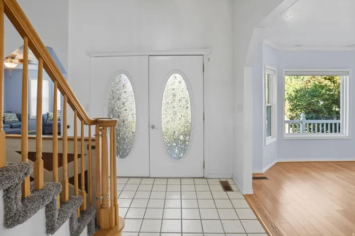 Entryway featuring french doors, a ceiling fan, light tile patterned floors, and crown molding