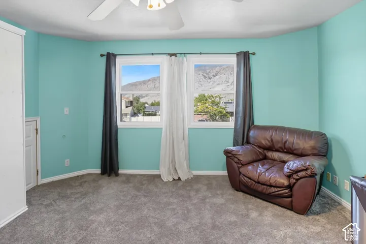 Sitting room with carpet flooring, ceiling fan, and a mountain view