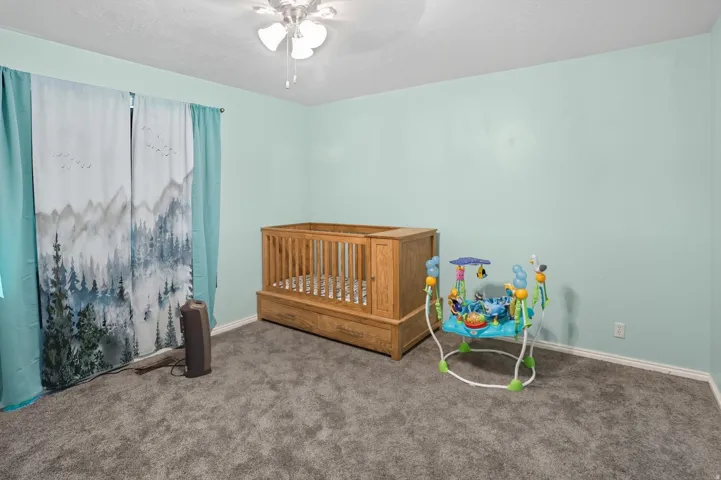 Bedroom with carpet floors, ceiling fan, and a textured ceiling