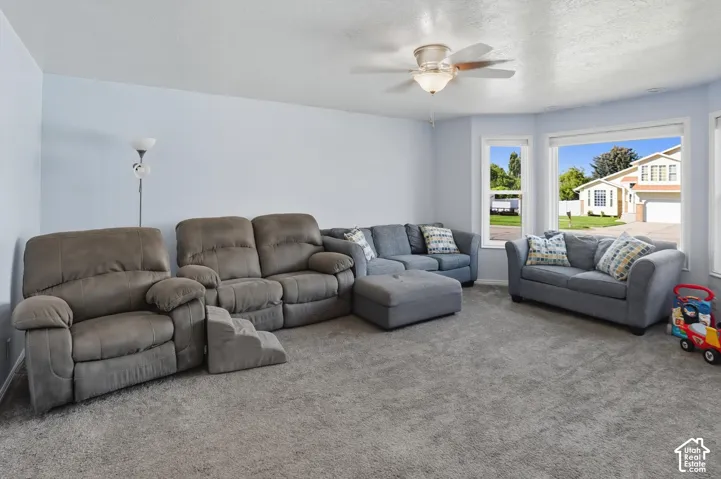 Carpeted living room featuring a ceiling fan and a textured ceiling