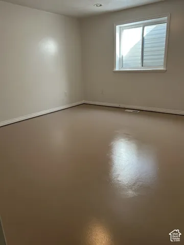Room featuring a window with an external window well, smooth-finish walls, and polished solid-surface flooring with recessed lighting