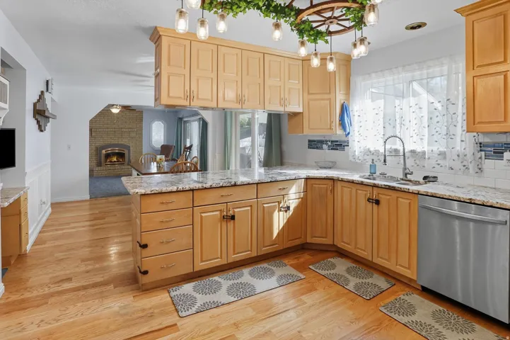 Kitchen with a peninsula, dishwasher, light stone counters, and open floor plan