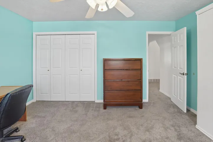 Carpeted home office with a textured ceiling and ceiling fan