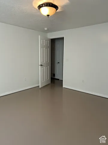 Room featuring neutral wall paint, smooth-finish flooring, a six-panel interior door, and a flush-mount dome light fixture