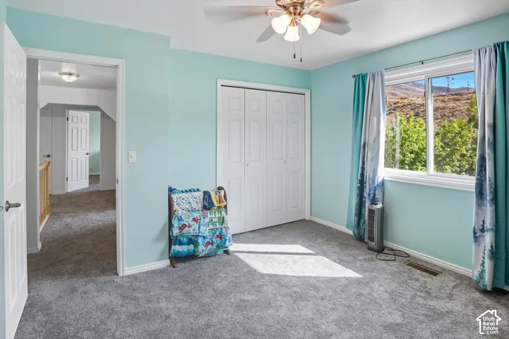 Unfurnished bedroom with carpet floors, a closet, a ceiling fan, and a mountain view