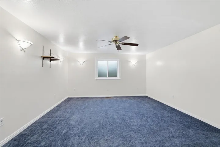 Empty room with dark carpet and ceiling fan