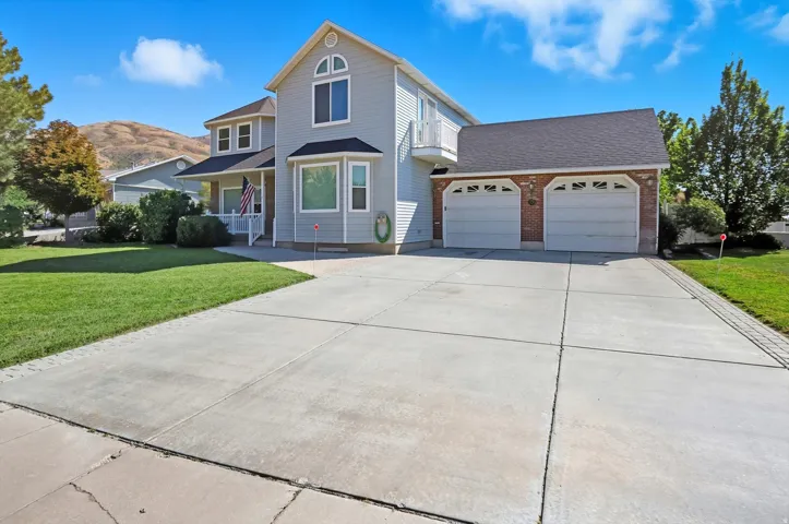 Traditional home with a front lawn, concrete driveway, an attached garage, and roof with shingles