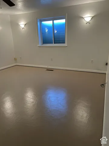 Room featuring a polished concrete floor, dual wall-mounted semi-flush light fixtures, and a sliding window