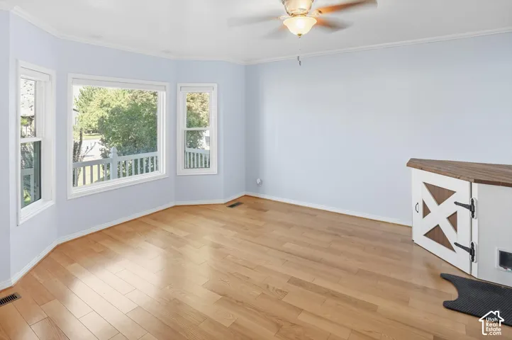 Unfurnished room with light wood finished floors, a ceiling fan, and crown molding