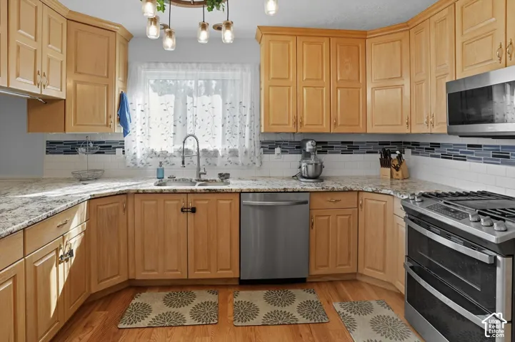 Kitchen with stainless steel appliances, light stone counters, and tasteful backsplash