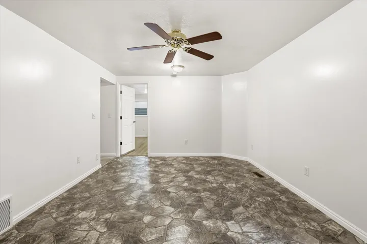 Unfurnished room with stone floors and ceiling fan