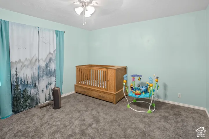Bedroom with carpet floors, ceiling fan, and a textured ceiling