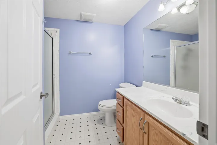 Full bath with a stall shower, light floors, vanity, and a textured ceiling