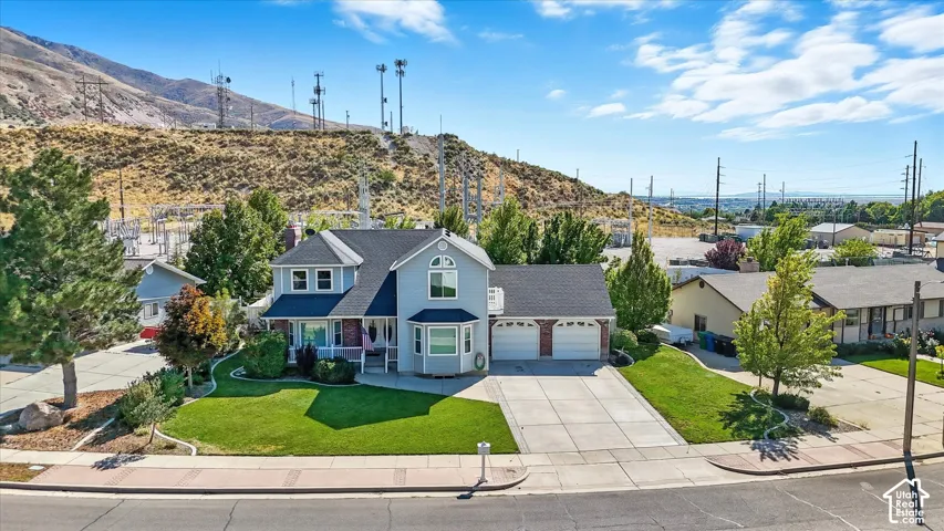 Traditional home with a front lawn, driveway, a residential view, an attached garage, and a mountain view