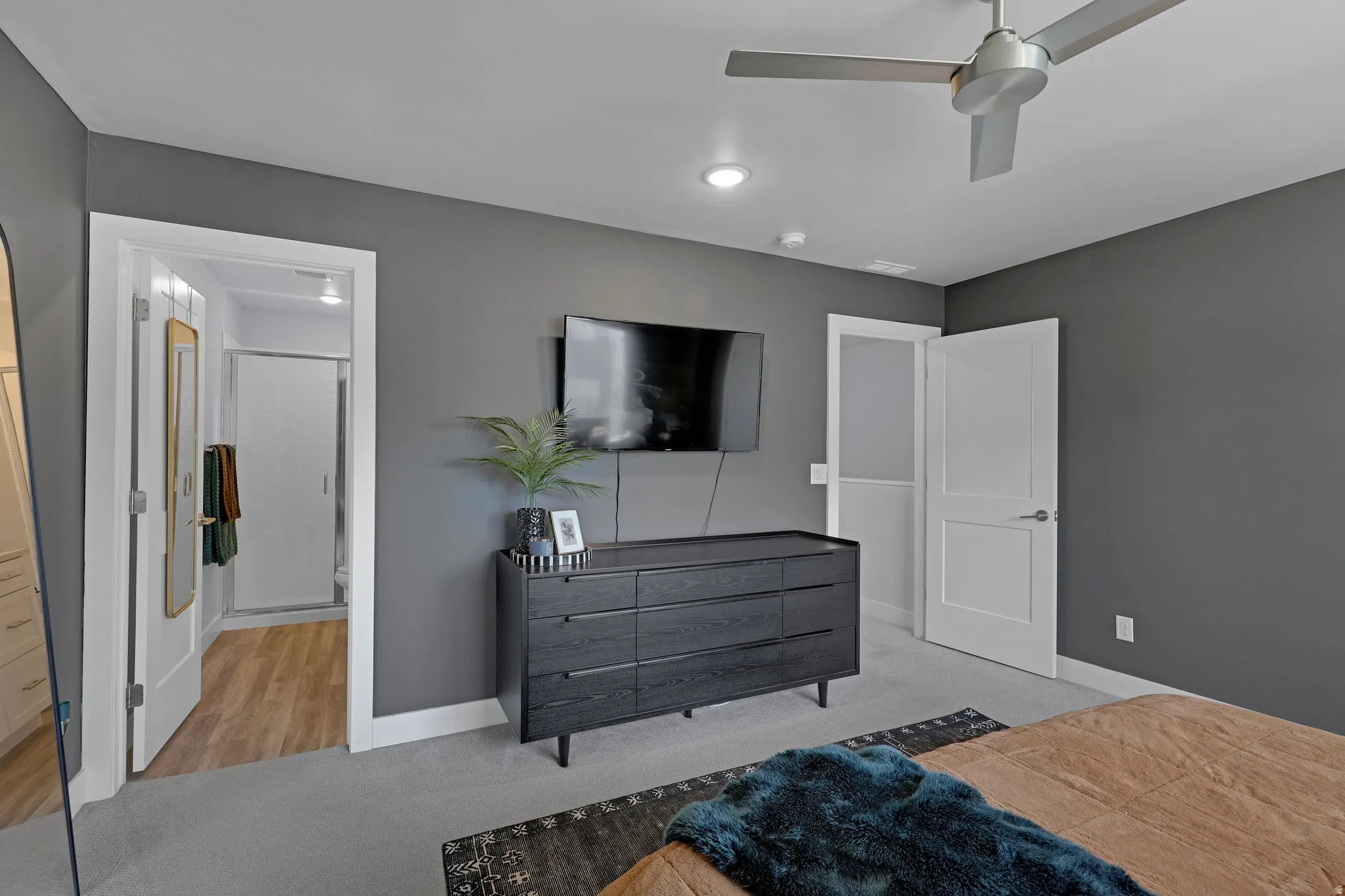 Bedroom with light colored carpet, ceiling fan, and ensuite bathroom