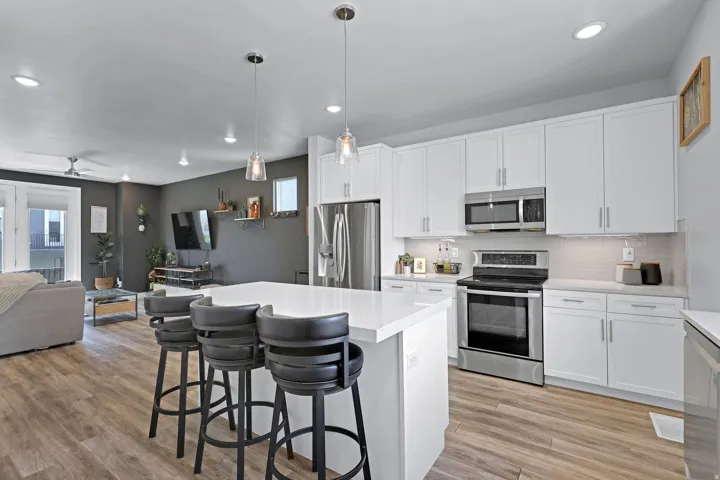 Kitchen featuring stainless steel appliances, white cabinets, open floor plan, a kitchen bar, and a kitchen island