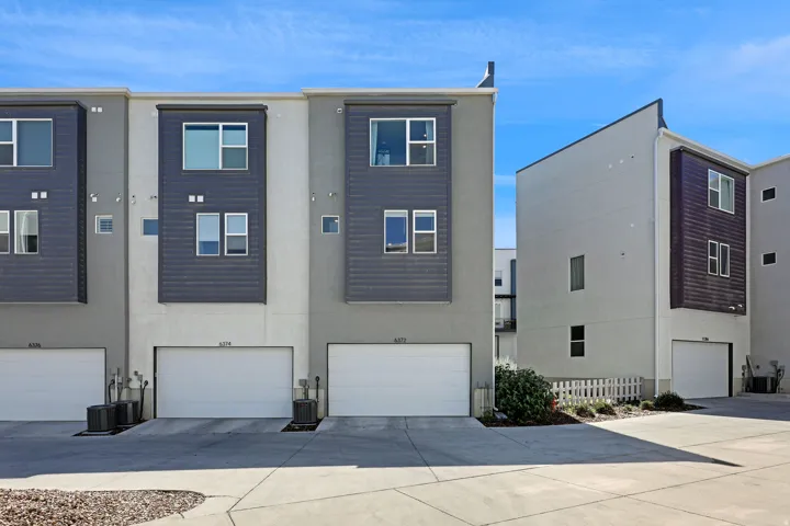 Rear view of property with stucco siding, a garage, and driveway