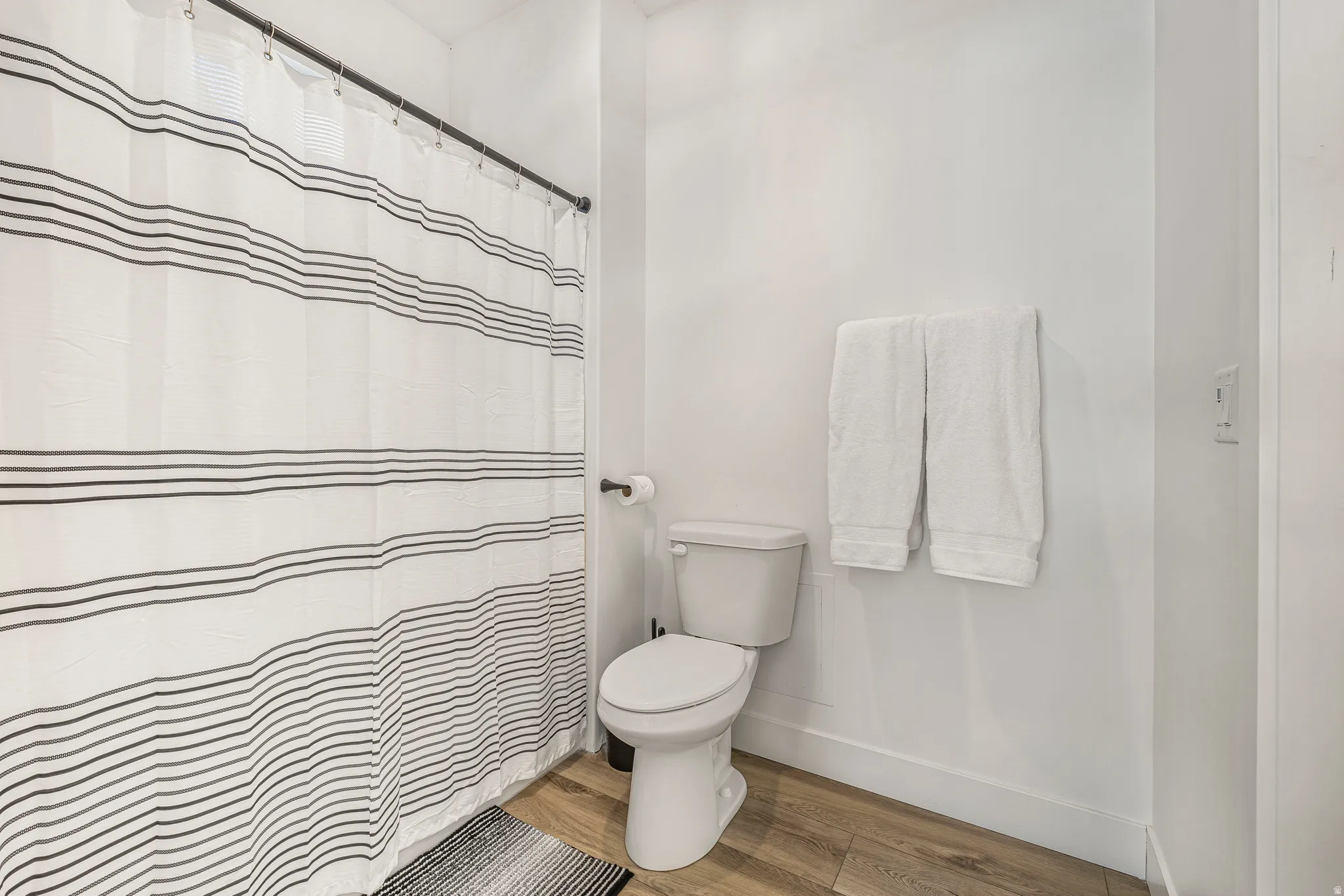 Full bath featuring a shower with shower curtain and light wood finished floors