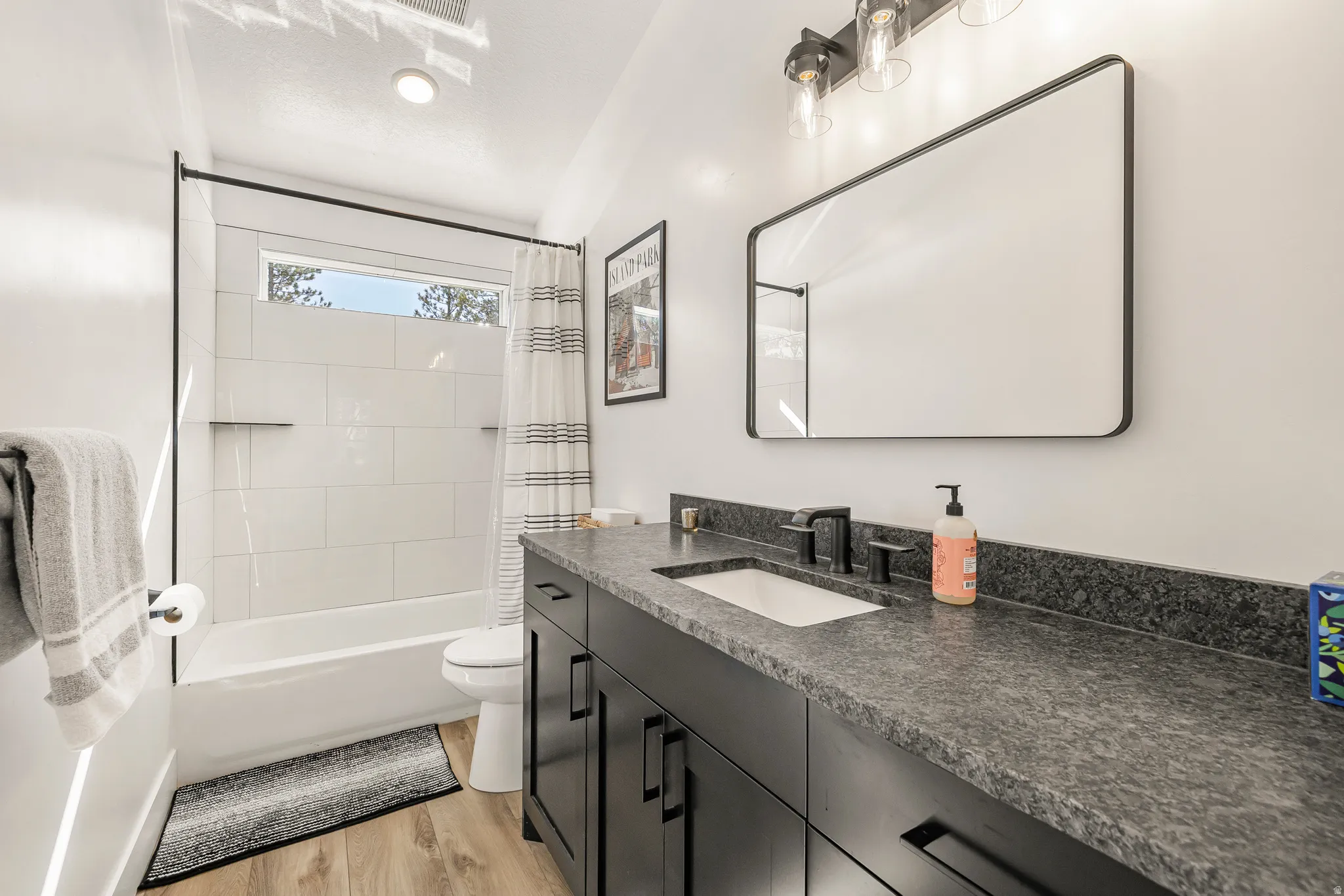 Full bath with vanity, shower / bath combo, and light wood finished floors