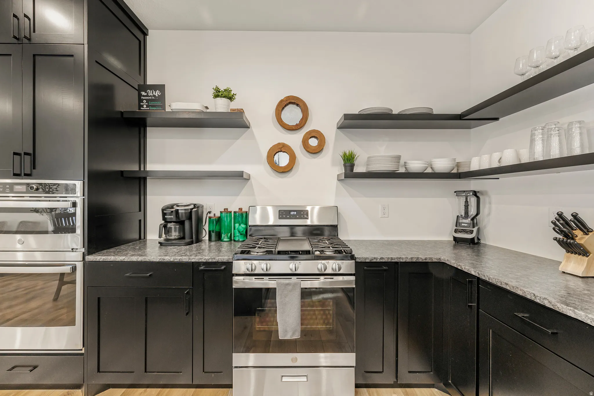 Kitchen with dark cabinetry, stainless steel appliances, and open shelves