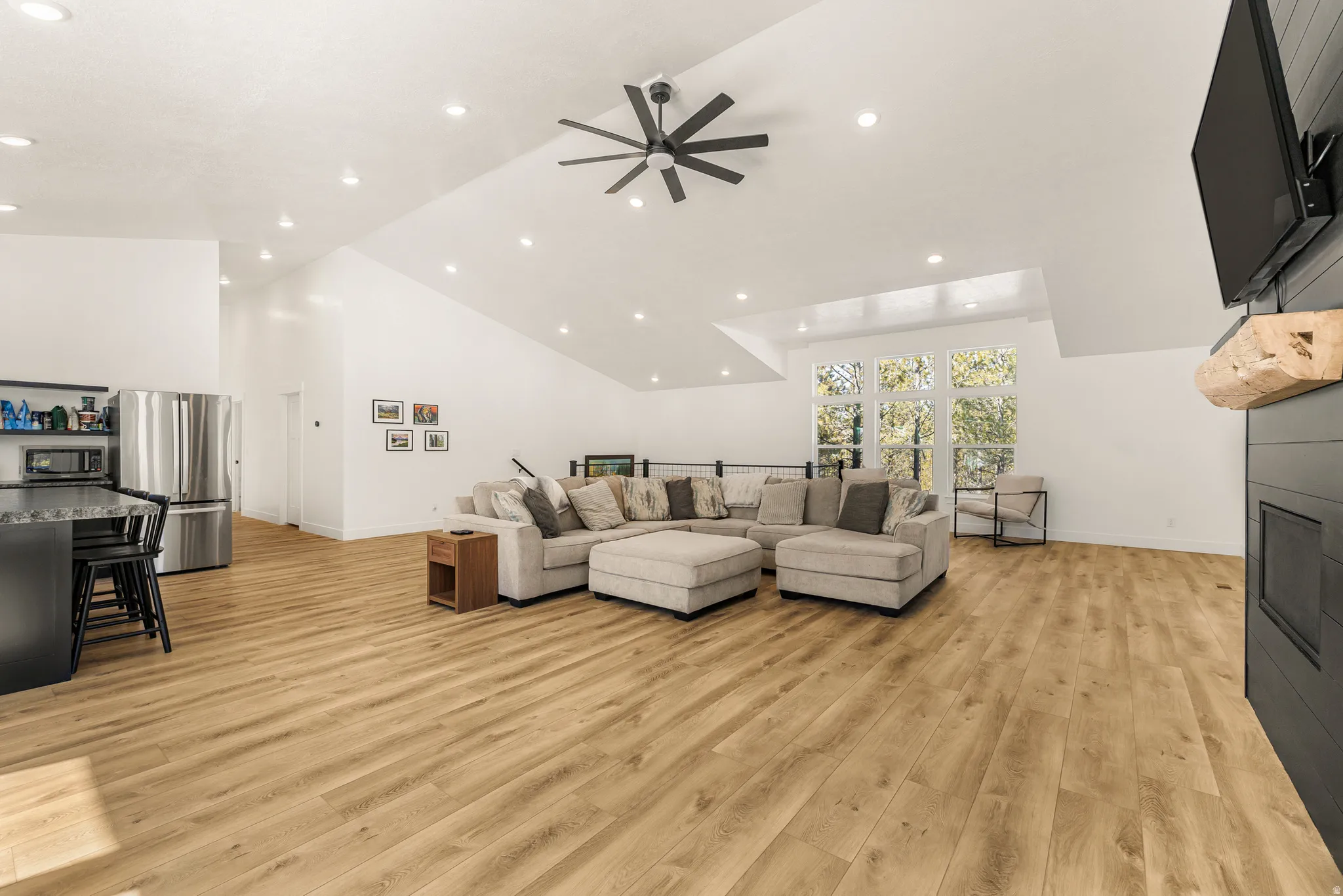 Living area featuring light wood-style flooring, a ceiling fan, lofted ceiling, recessed lighting, and a large fireplace