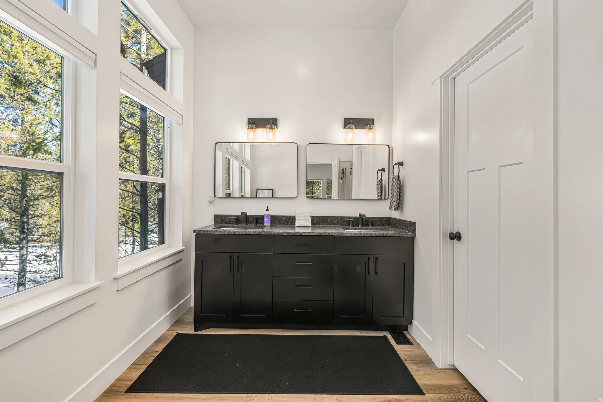 Full bath with light wood finished floors and double vanity