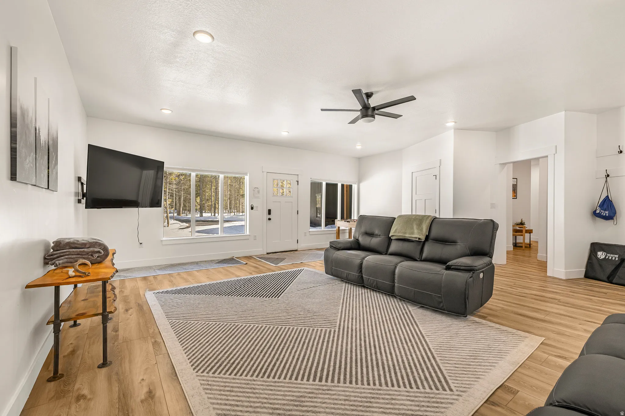 Living area with light wood-type flooring, a ceiling fan, and recessed lighting
