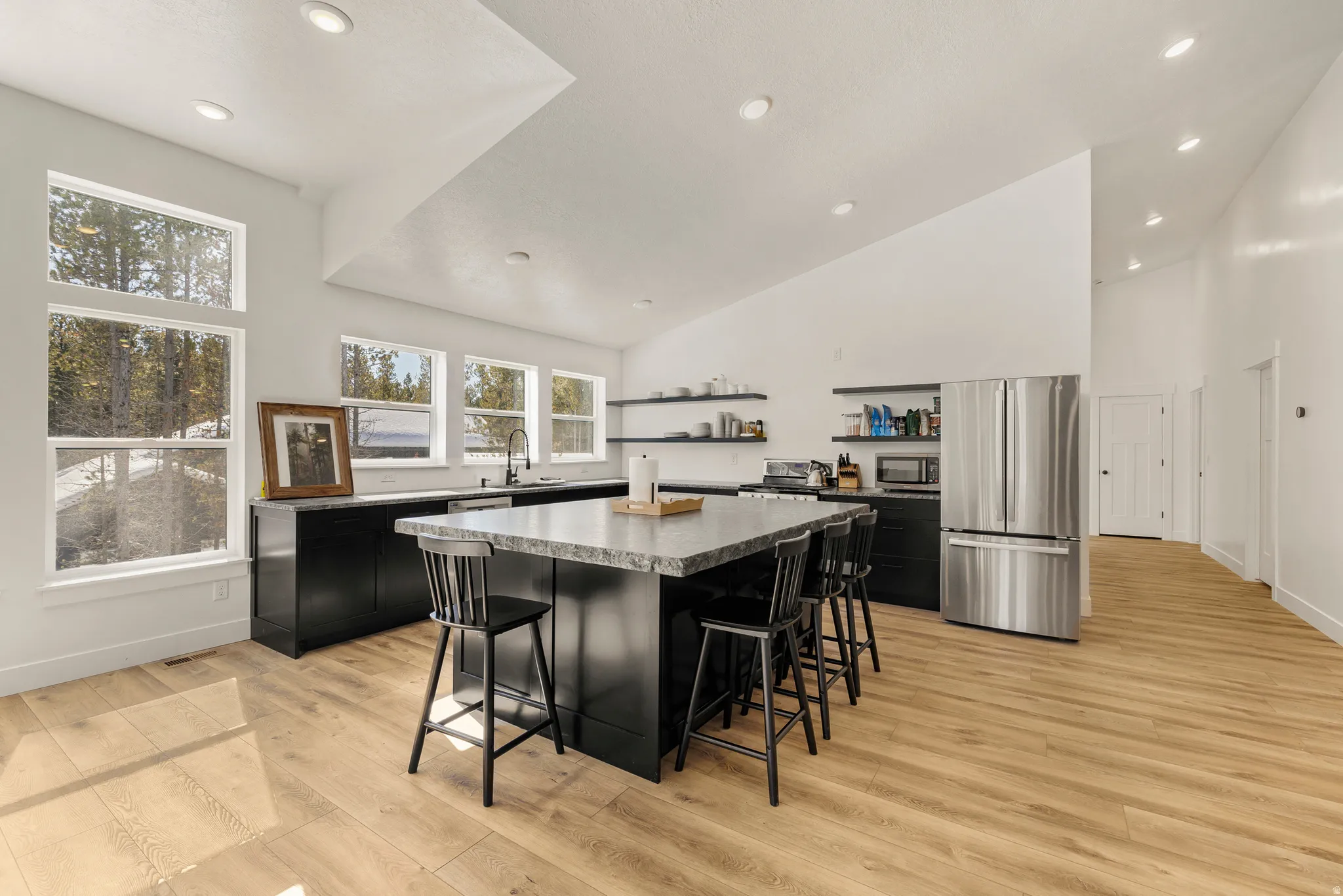 Kitchen with dark cabinets, a center island, stainless steel appliances, a breakfast bar area, and light wood finished floors