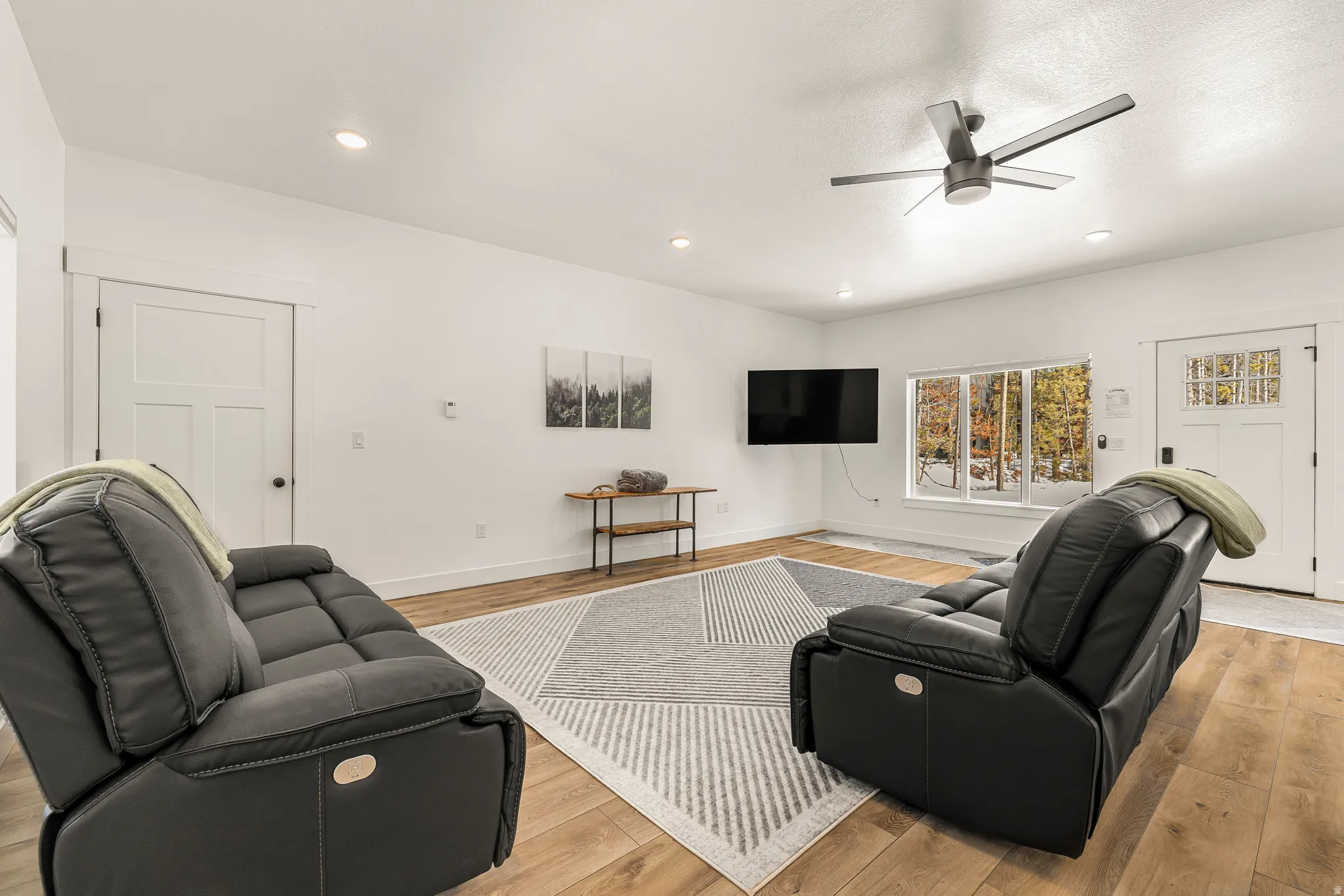 Living room with light wood finished floors, ceiling fan, and recessed lighting