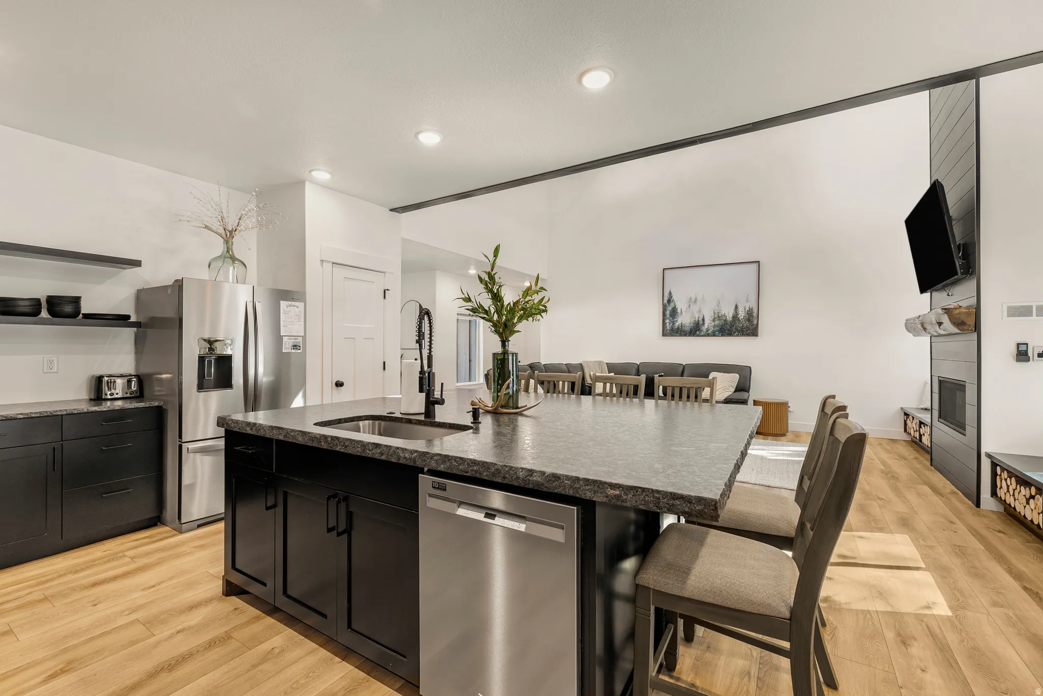 Kitchen featuring a kitchen bar, stainless steel appliances, an island with sink, dark cabinetry, and recessed lighting