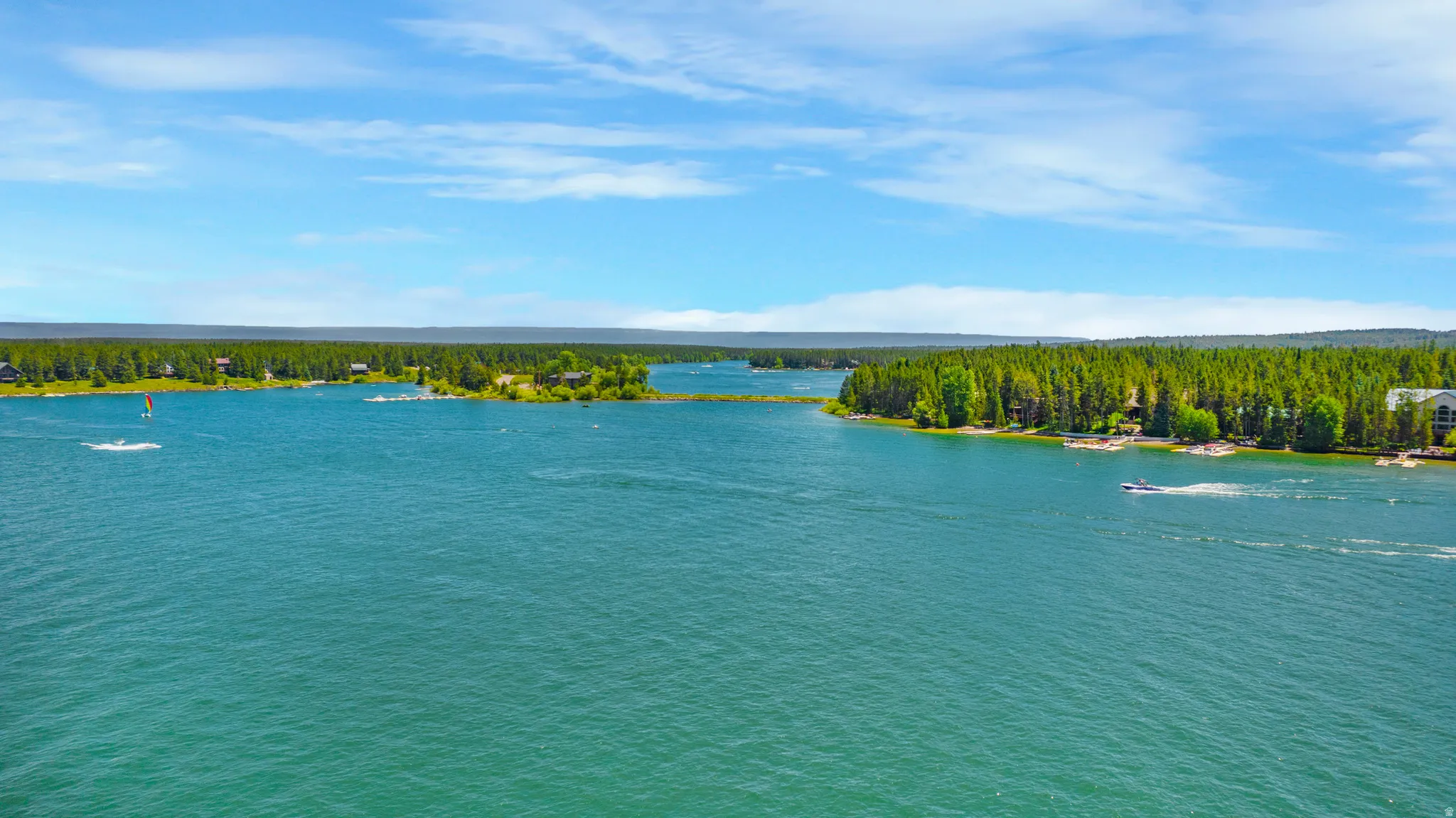 Expansive waterfront property featuring a large body of water, dense tree lines, and distant structures
