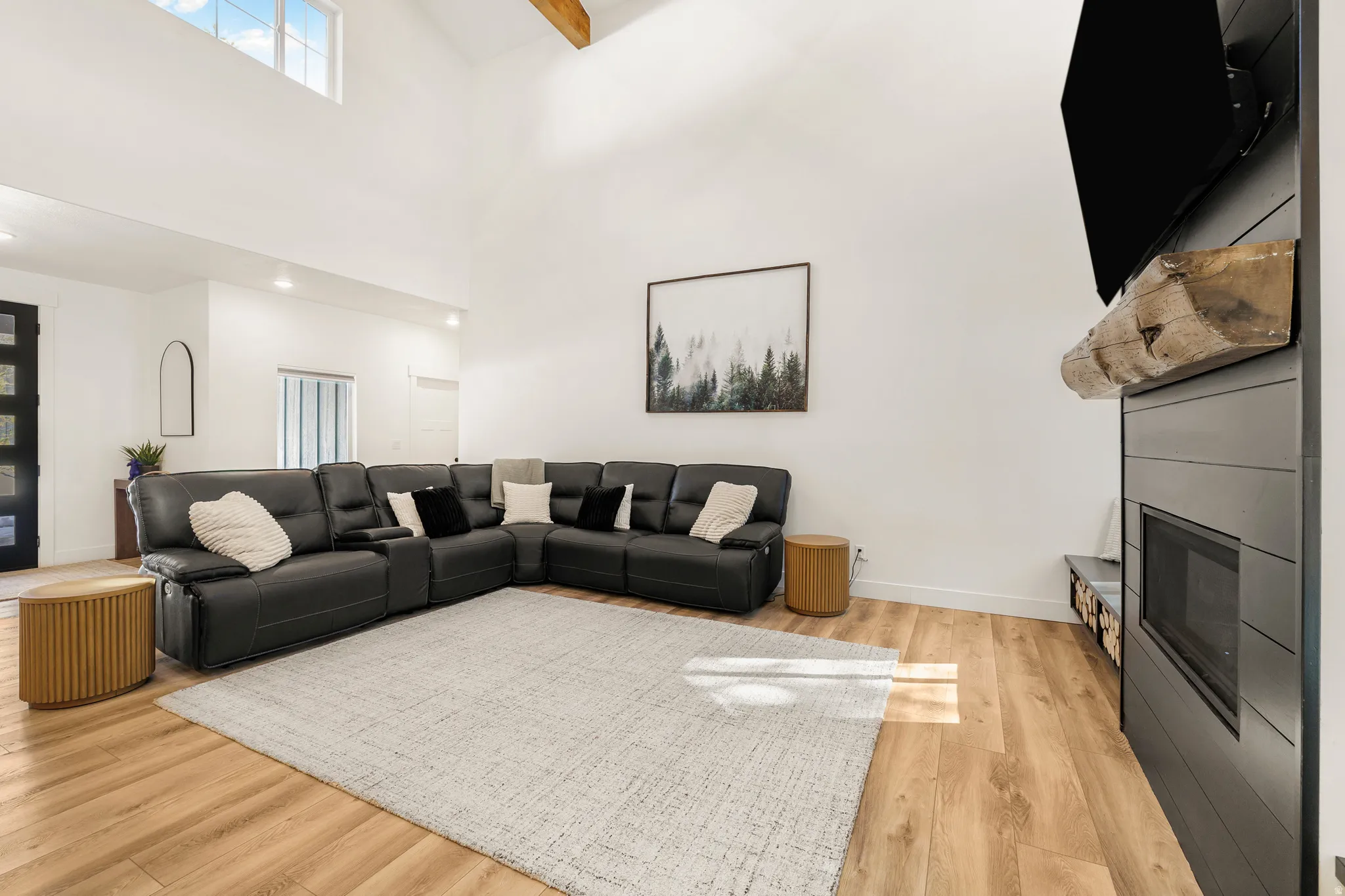 Living room featuring light wood-style flooring, a fireplace, and a high ceiling