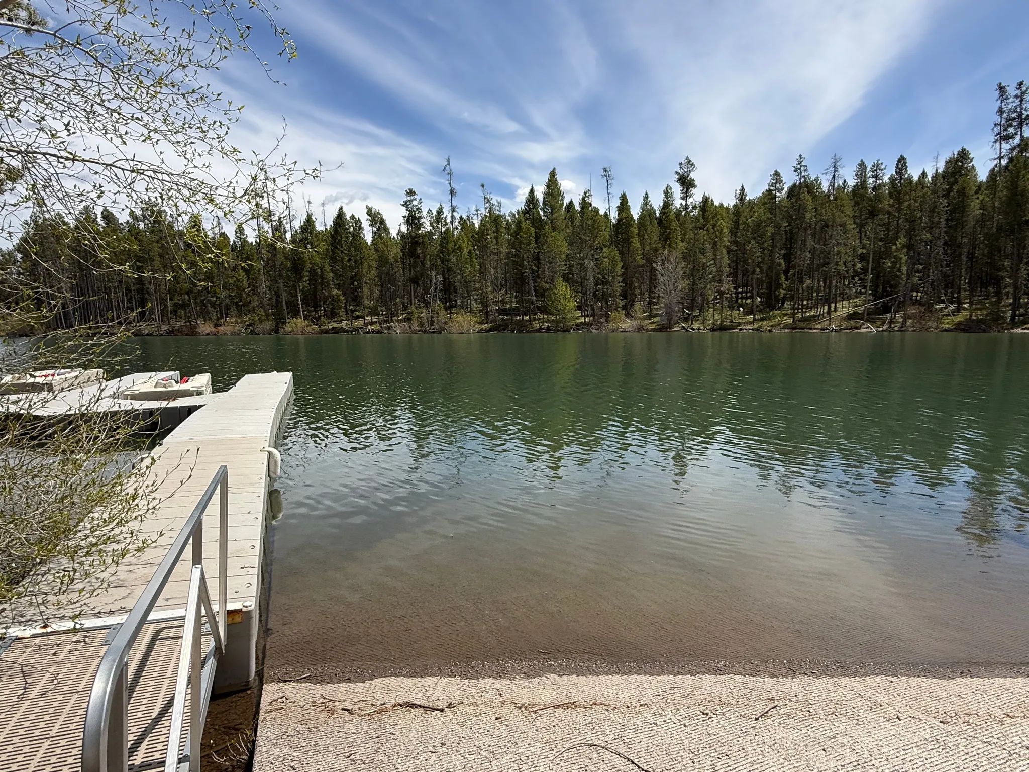 Lakefront property featuring a private boat dock, adjacent boat launch, and a forested shoreline