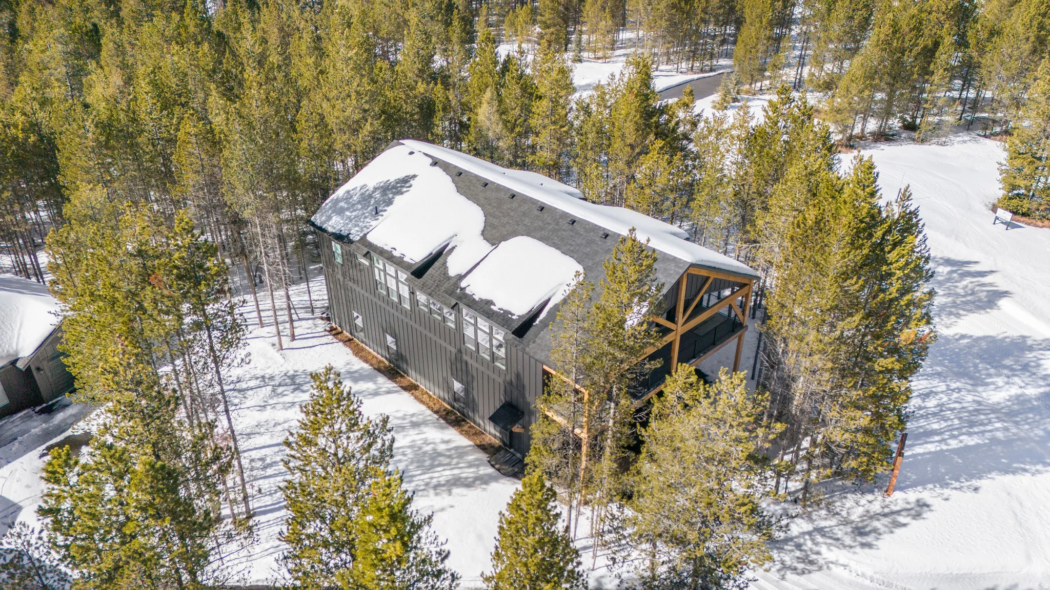 Snowy aerial view with view of wooded area